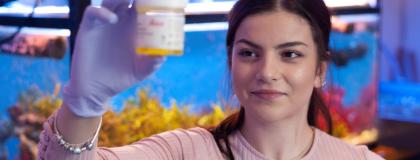 person in front of aquarium holding sample