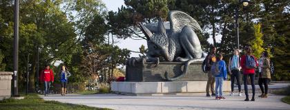 Group of students standing around the Gryphon statue on campus.