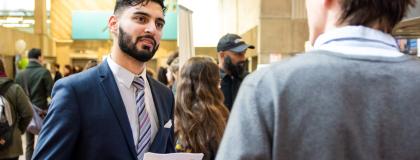 younger man in suit talking to older man while holding resume